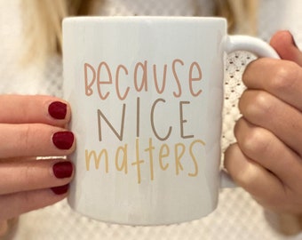 May include: White ceramic mug with a black handle. The mug has the text "because nice matters" written in black and brown lettering.