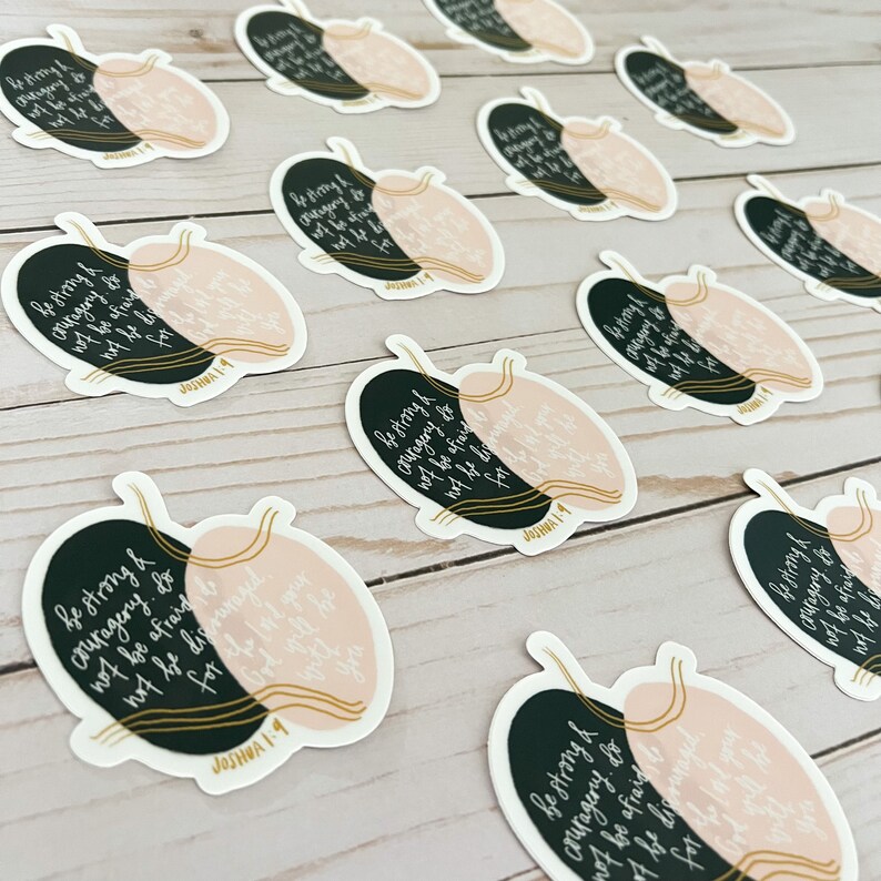 May include: A set of black and pink round stickers with gold accents. The stickers feature the text "Be strong and courageous. Do not be afraid, do not be discouraged, for the Lord your God will be with you." and "Joshua 1:9".