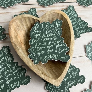 May include: Green and white sticker with the text "For I know the plans I have for you," declares the Lord. "Plans to prosper you and not to harm you, plans to give you a hope and a future." Jeremiah 29:11