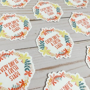 Peut inclure: Un ensemble de huit autocollants floraux avec le texte "Every day is a fresh start!" dans un cercle blanc entour&eacute; d'une couronne de fleurs dans des tons de rose, jaune et vert.