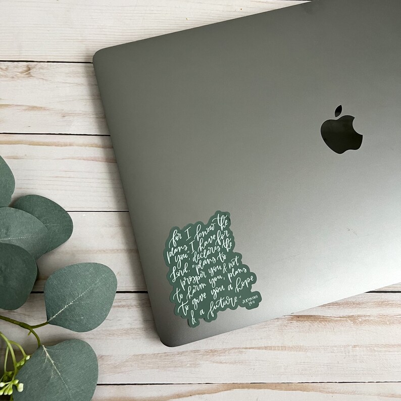 May include: A green sticker with white lettering on a silver laptop. The sticker features a quote from the Bible: "For I know the plans I have for you," declares the Lord, "plans to prosper you and not to harm you, plans to give you hope and a future." - Jeremiah 29:11