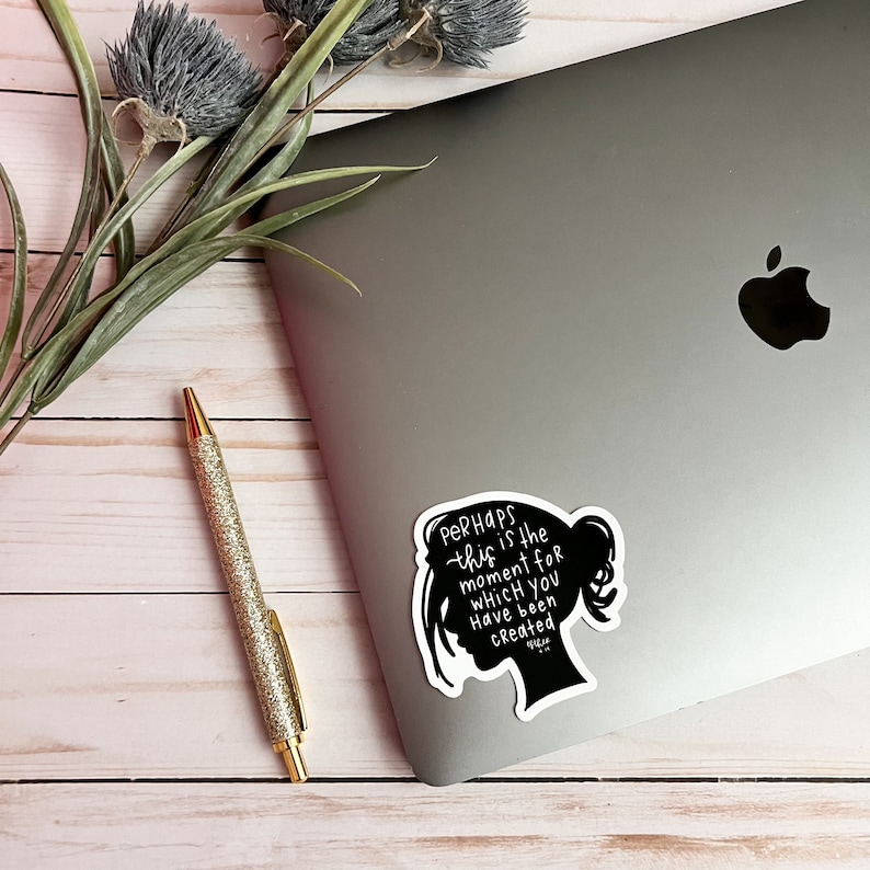 May include: Black and white sticker with a silhouette of a woman's head and the text "Perhaps this is the moment for which you have been created."