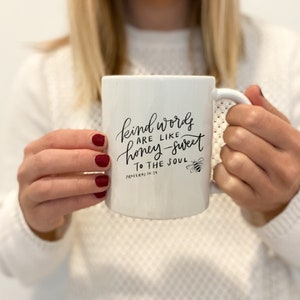 May include: White ceramic mug with black lettering that reads "Kind words are like honey-sweet to the soul, Proverbs 16:24". A small bee illustration is next to the text.