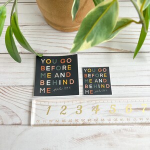 May include: Two black square stickers with the text "You go before me and behind me" in colourful letters. The text is from Psalm 139:5.