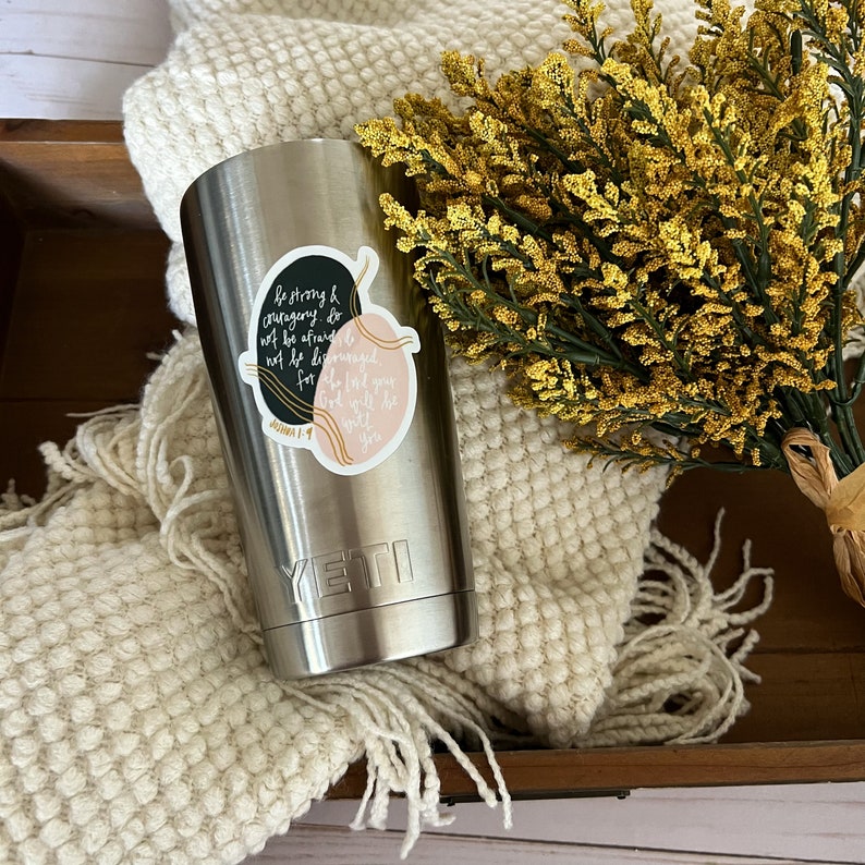 May include: A stainless steel Yeti tumbler with a black and pink sticker that reads "be strong & courageous do not be afraid not be discouraged for the Lord your God will be with you" and the scripture reference "Joshua 1:9".