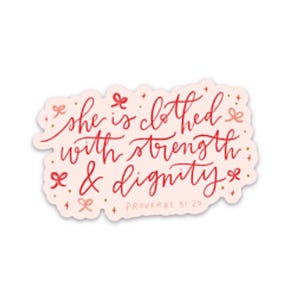 May include: A sticker with the quote "she is clothed with strength & dignity" in red script on a light pink background. The sticker has small bow and star accents. The Bible verse Proverbs 31:25 is also included.