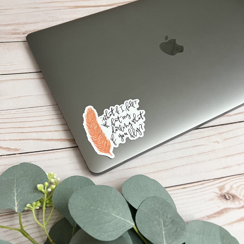 Op de afbeelding: Een sticker met een verenpatroon en de tekst "what if I fell? oh but my darling what if you fly?"
