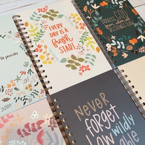 May include: Four different spiral bound journals with floral designs and inspirational quotes. The quotes are "He provides", "Every day is a fresh start", "Praise God from whom all blessings flow", and "Never forget how wildly able".