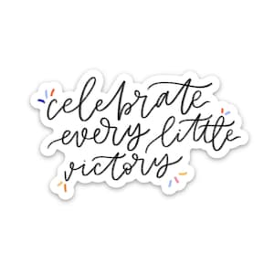 May include: Black and white sticker with the text "celebrate every little victory" in a handwritten font. The sticker has a white border and colorful confetti around the edges.