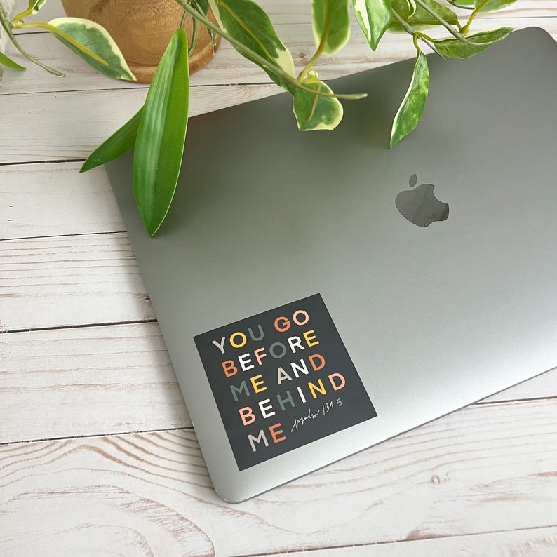 May include: A black square sticker with colourful text that reads "You go before me and behind me" with the scripture reference "Psalm 139:5" written in cursive.