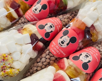 May include: Transparent cellophane bags filled with a variety of sweets, such as marshmallows, gummy sweets, and chocolate-covered treats. Each bag features a red Mickey Mouse sticker with the text "Thanks for coming to Jacob's Party!"