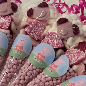 May include: Clear cellophane bags filled with pink sweets, marshmallows, and candies. Each bag features a sticker with a cartoon pig and the text "Happy Birthday Emma". Pink ribbons and various sweets are also visible.