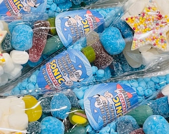 May include: Blue and white party favor cones filled with colorful candies. The cones have a Sonic the Hedgehog theme and say "Thank you for celebrating Freddie's 6th birthday".