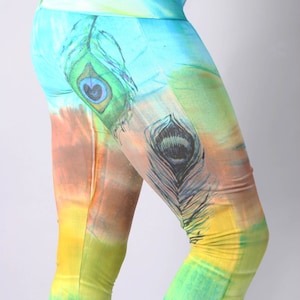 May include: A pair of colourful leggings with a peacock feather design. The leggings are a mix of blue, green, yellow, and brown.