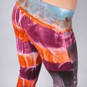 May include: A pair of colorful leggings with a tie-dye pattern in shades of orange, pink, and purple. The leggings have a wide waistband and a fitted silhouette.