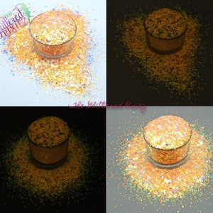 Könnte beinhalten: Nahaufnahme eines Glases mit orangefarbenem, gelbem und schimmerndem Glitter. Der Glitter wird in vier verschiedenen Lichtverhältnissen gezeigt: Tageslicht, Dunkelheit, Schwarzlicht und eine Kombination aus Tageslicht und Schwarzlicht. Der Glitter leuchtet hell unter Schwarzlicht.
