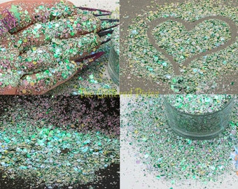 May include: A close-up of iridescent green, blue, and gold glitter. The glitter is shown in a variety of ways, including in a hand, in a heart shape, and in a glass jar.