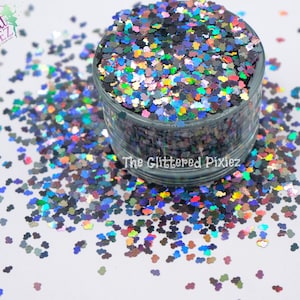 Może przedstawiać: Zbliżenie na słoik wypełniony tęczowym holograficznym brokatem w kształcie głów Myszki Miki. Brokat jest rozrzucony na białym tle.