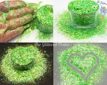 May include: Green iridescent glitter with a holographic finish. The glitter is shown in a small glass jar and scattered on a surface. The glitter is also shown in a heart shape.