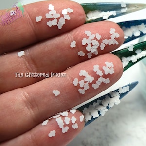 May include: White cloud shaped glitter, scattered on a hand and nails. The glitter is small and has a subtle shine.