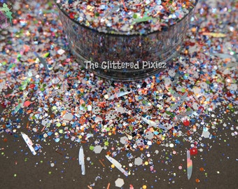 May include: A close-up of a variety of colorful glitter, including iridescent, holographic, and opaque glitter. The glitter is in a clear glass jar and is spilling out onto a dark surface. The glitter is a mix of different sizes and shapes.