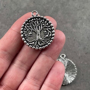 Puede incluir: Encanto de plata con un diseño de árbol de la vida. El encanto es redondo y tiene un borde de cuentas.