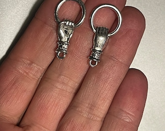 May include: Two silver-toned metal charms shaped like a hand holding a ring. The charms are intricately designed and ideal for adding a unique touch to jewellery or crafts.