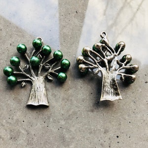Pode incluir: Dois pingentes de árvore de metal prateado com contas de vidro verde para as folhas. As árvores têm um aspeto rústico e antigo.