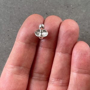 May include: A silver-toned metal spinning top with a rounded top and a flat base.