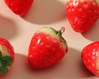 May include: Five red and green strawberry shaped charms with a gold loop for hanging. The strawberries have a white center and red seeds.