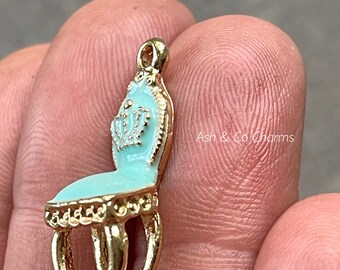 May include: A gold charm in the shape of a small, ornate chair. The chair is painted a light blue color with white accents and has gold legs.