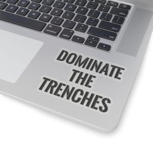 Könnte beinhalten: Ein Laptop mit einem Aufkleber, auf dem in schwarzer Schrift auf weißem Hintergrund "Dominate the Trenches" steht.