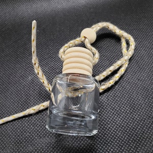 May include: A clear glass bottle with a wooden cap and a white string attached. The bottle is hanging from a wooden bead.