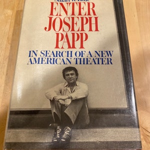May include: A book titled "Enter Joseph Papp: In Search of a New American Theater" by Stuart W. Little. The cover features a black and white photo of Joseph Papp sitting on a step.
