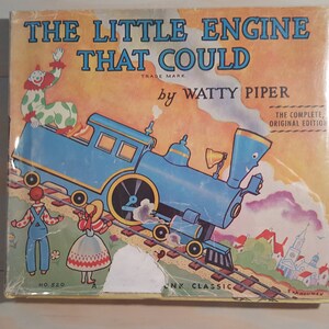 Könnte beinhalten: Ein Vintage-Buchcover mit einer blauen Lokomotive, die einen Wagen einen Hügel hinaufzieht. Der Buchtitel lautet "The Little Engine That Could" von Watty Piper. Das Cover zeigt auch einen Clown, ein Mädchen und einen Jungen.