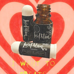 May include: An image showing three aromatherapy products: a small brown glass bottle labelled "Love Potion massage oil" and two inhalers. The inhalers and bottle have black labels with white text. The background is a red and white heart pattern with the text "I WANT TO CREATE MEMORIES".