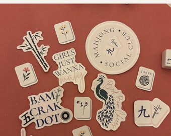 May include: A collection of twelve Mahjong-themed stickers featuring various designs including a peacock, bamboo stalks, floral tiles, and text such as Mahjong Club Social, Girls Just Wanna Mahj, Bam Crak Dot, and Mahj Mom on a solid terracotta background.