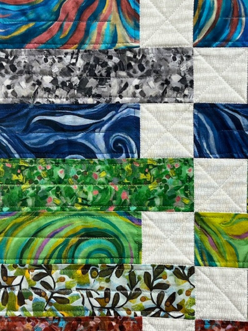 K&ouml;nnte beinhalten: Ein Patchwork-Deckenst&uuml;ck mit einer Vielzahl von bunten Stoffen. Die Decke besteht aus Quadraten, die jeweils ein anderes Muster aufweisen. Die Muster umfassen Wirbel, Blumen und geometrische Formen. Die Decke ist mit wei&szlig;em Garn zusammengen&auml;ht.