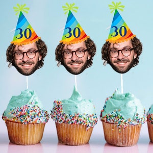 May include: Three cupcakes decorated with colorful sprinkles and topped with a birthday hat featuring a face cutout and the number "30".