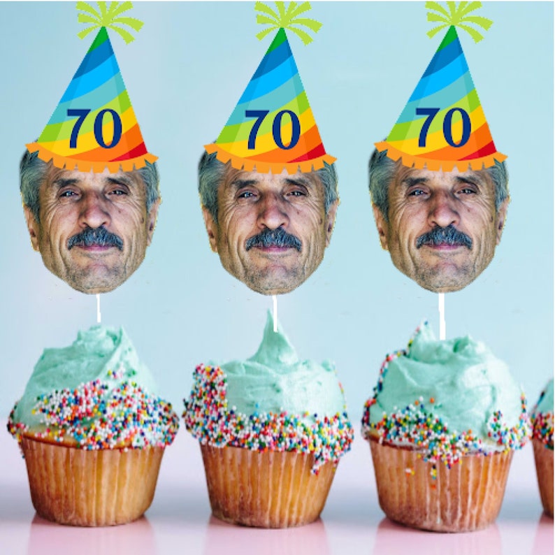 May include: Three cupcakes with blue frosting and colorful sprinkles. Each cupcake has a birthday hat with the number 70 on it. The hats are rainbow colored with a green star on top.