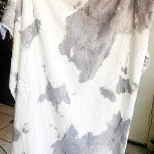 May include: A soft, white and gray faux fur throw blanket with a cloud-like pattern.