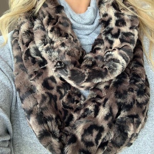 May include: A brown and black faux fur infinity scarf with a leopard print pattern.