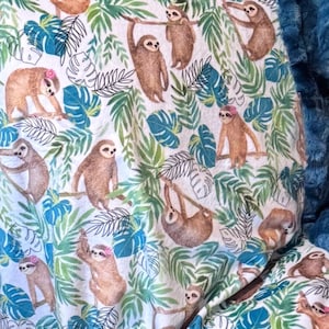 May include: A white fabric with a repeating pattern of brown sloths, green and blue tropical leaves, and black line art. The sloths are in various poses, some hanging from branches. A blue, textured border is visible.