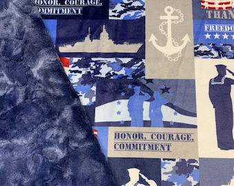 May include: A blue and white fleece blanket with a patriotic theme. The blanket features anchors, stars, stripes, and the words "Freedom is not free", "Honor, Courage, Commitment", and "Than Freedom".