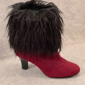 May include: A burgundy ankle boot with a black faux fur trim. The boot has a pointed toe and a small, black heel. The boot is made of a suede-like material.