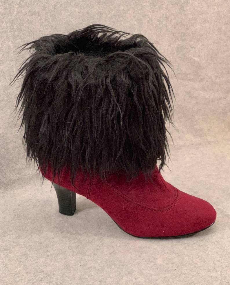 May include: A burgundy ankle boot with a black faux fur trim. The boot has a pointed toe and a small, black heel. The boot is made of a suede-like material.