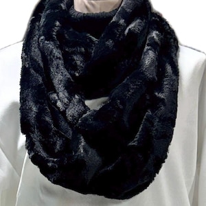 May include: A black faux fur infinity scarf. The scarf is soft and cozy, perfect for keeping warm in the winter.