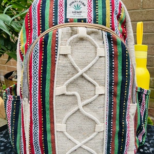 May include: A multi-coloured striped hemp backpack with a white hemp rope design. The backpack has a small pocket on the front and a label that reads "Himalayan Hemp THC Free Made in Nepal".