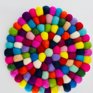 May include: A colorful round felt coaster made of many small balls of wool in various colors, including red, orange, yellow, green, blue, purple, pink, and white.