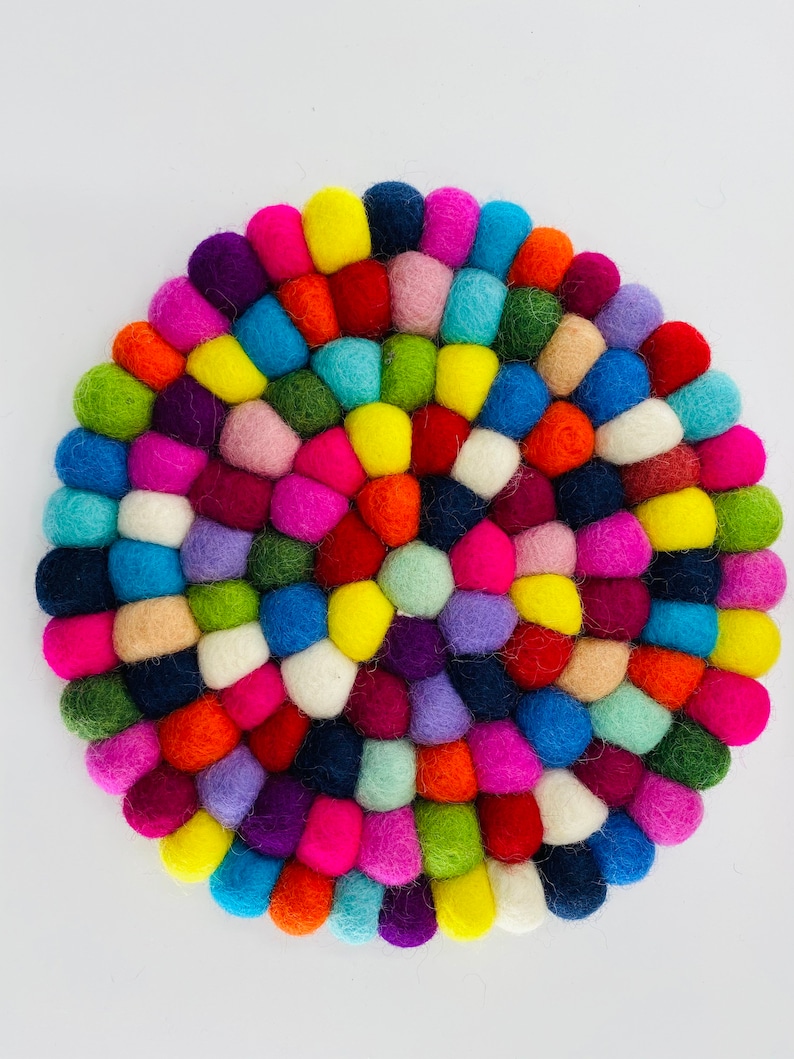 May include: A colorful round felt coaster made of many small balls of wool in various colors, including red, orange, yellow, green, blue, purple, pink, and white.
